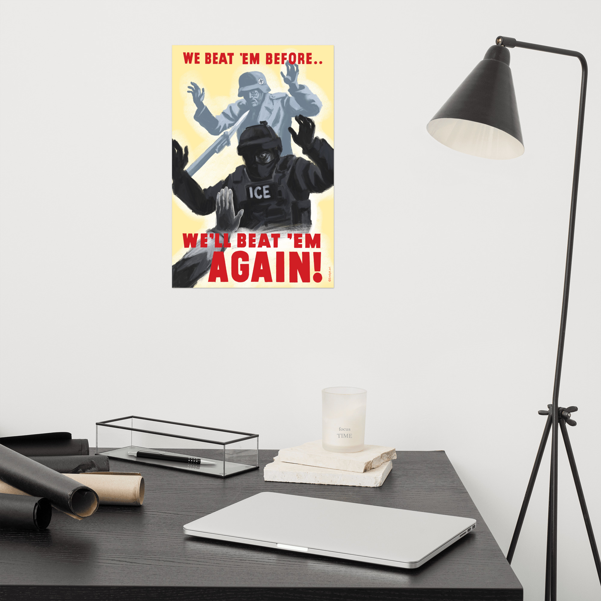 The print is hanging on a wall next to a desk lamp and above a desk.