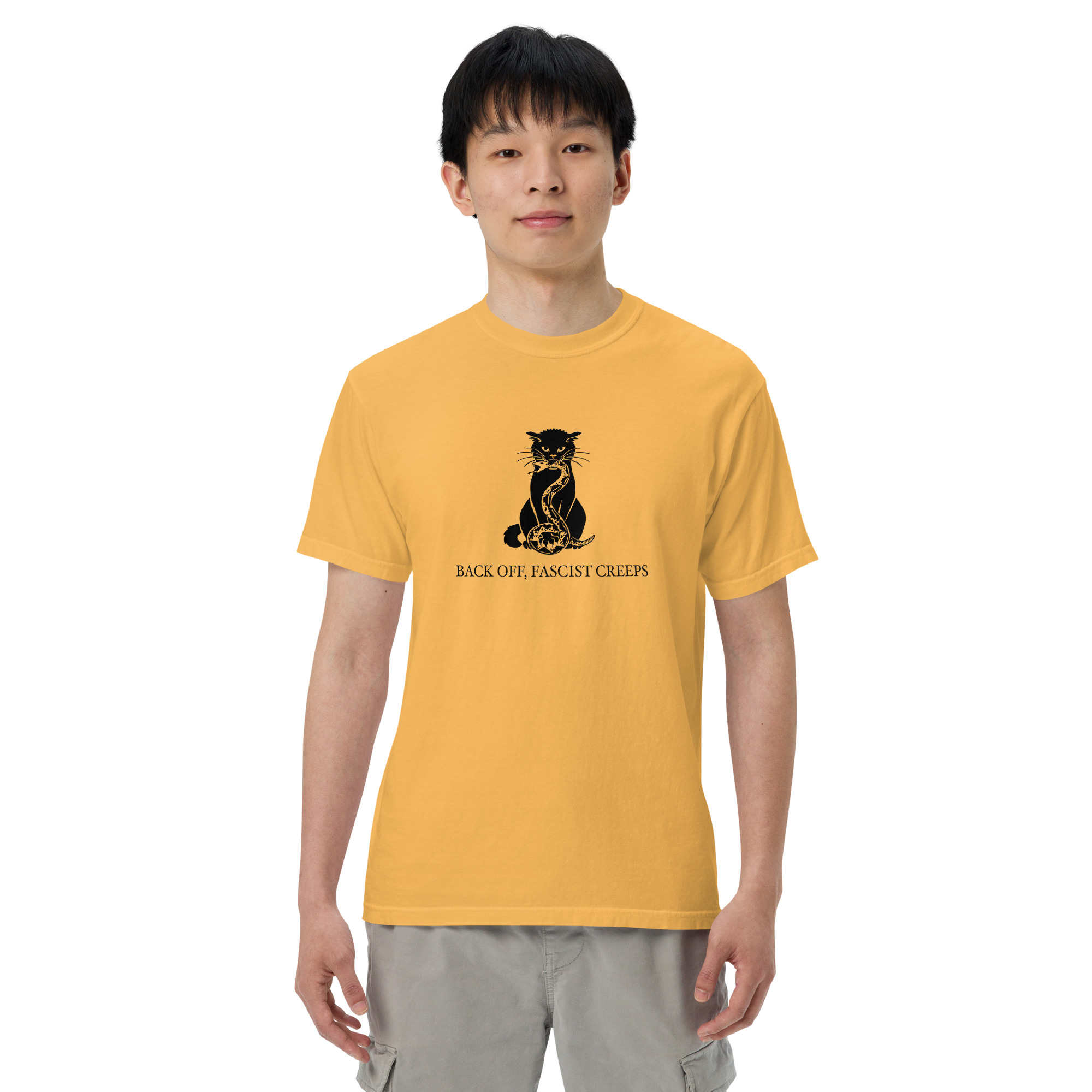 An average-sized man wearing a yellow T-shirt with a black cat crushing a snake in its mouth and under its paw. It says "Back off, Fascist creeps." He is looking straight at us.