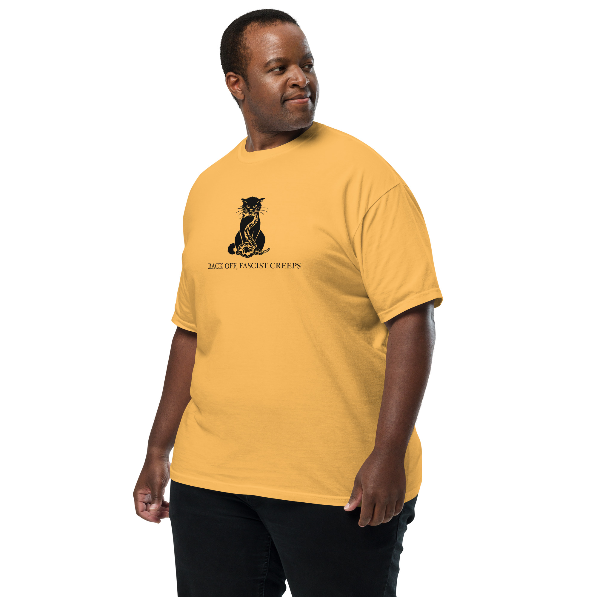 A big man wearing a yellow T-shirt with a black cat crushing a snake in its mouth and under its paw. It says "Back off, Fascist creeps." He is looking over his shoulder.